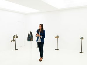 young caucasian art collector looking at contemporary sculptures displayed in a white exhibition space
